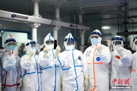 　图为李兰娟院士(左四)和团队成员在进入病房前加油鼓劲。中新社记者 安源 摄