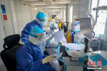 　　资料图：火神山医院感染二科一病区主任董宇超(白衣者)与同事一起查对患者信息。中新社记者 张畅 摄