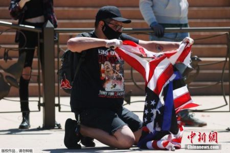 资料图：当地时间2020年5月29日，美国丹佛，示威者撕毁了一面美国国旗。